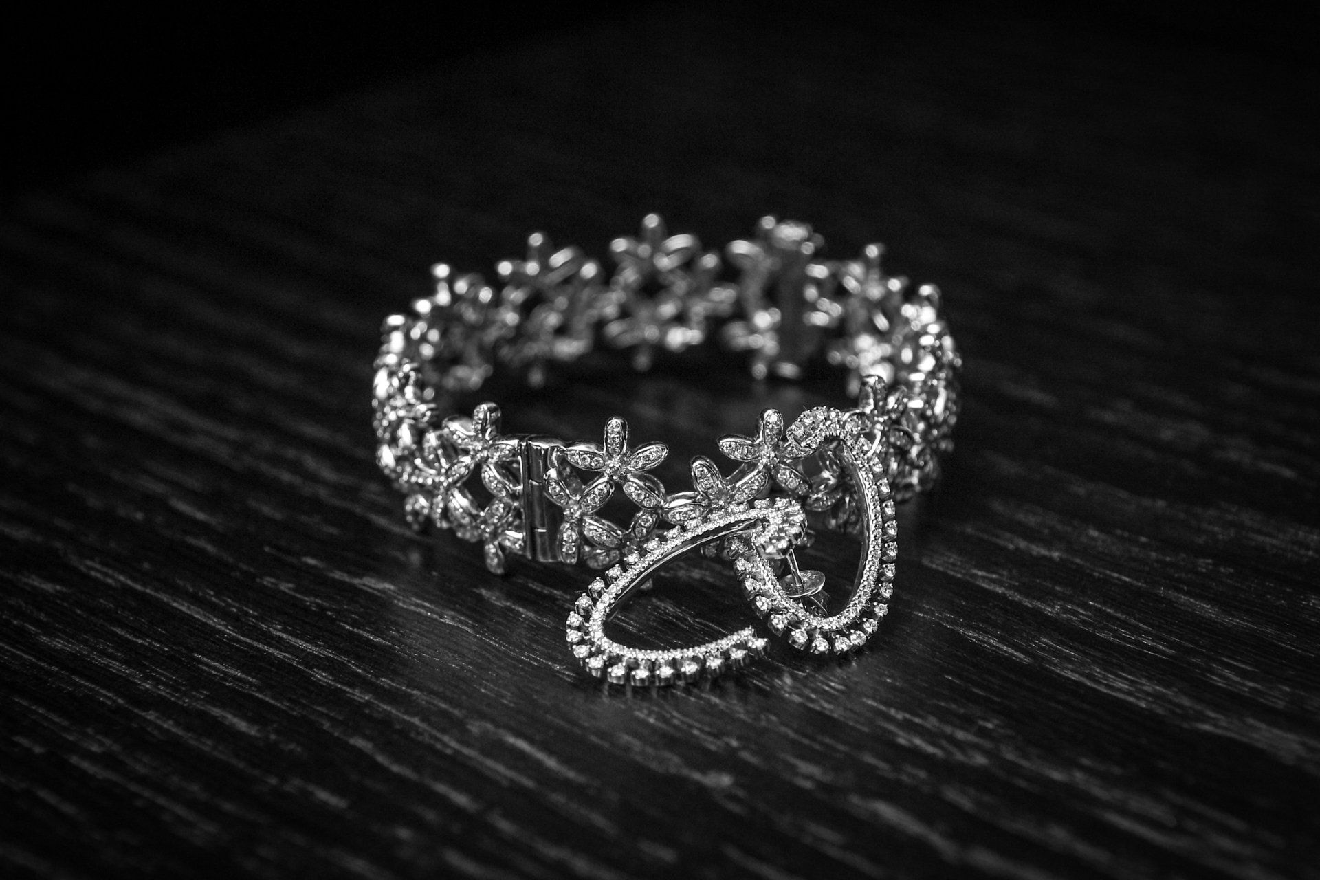 A black and white photo of a silver ring on a wooden table.