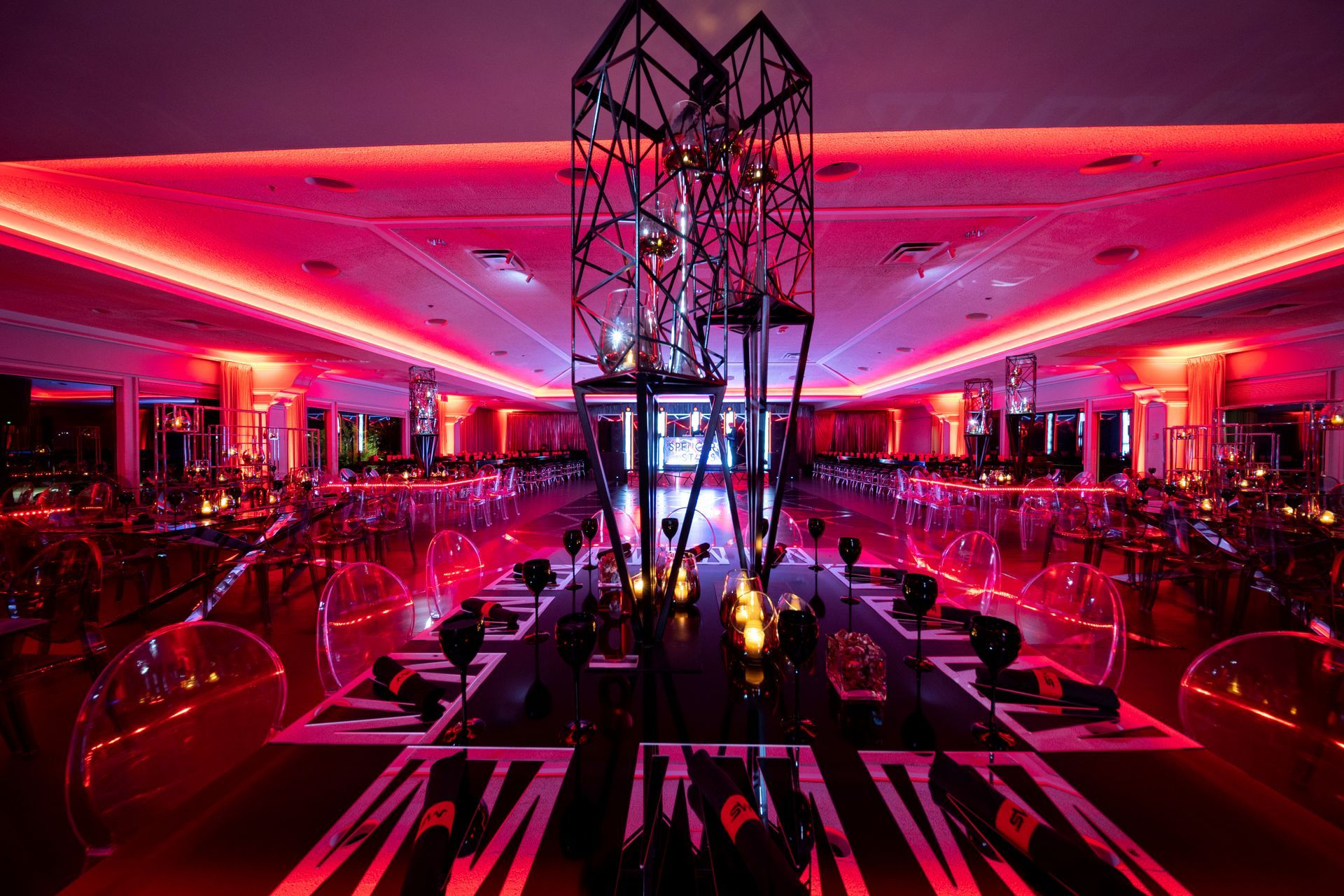 A large room with red lights on the ceiling and tables and chairs.