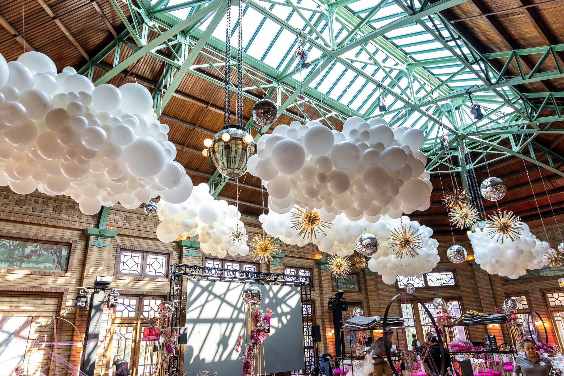 A bunch of white balloons are hanging from the ceiling of a building.