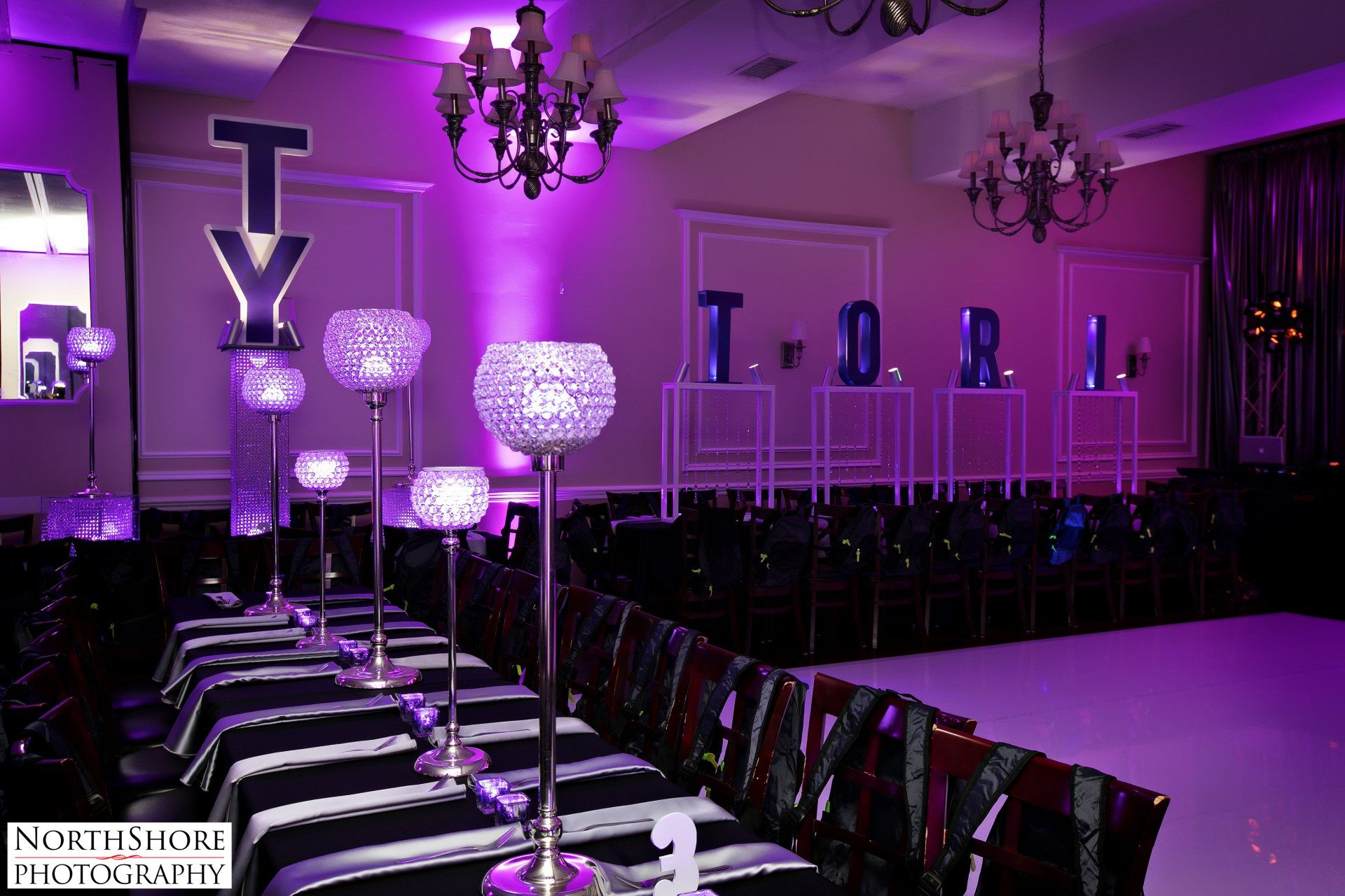 A large room with purple lights and tables and chairs