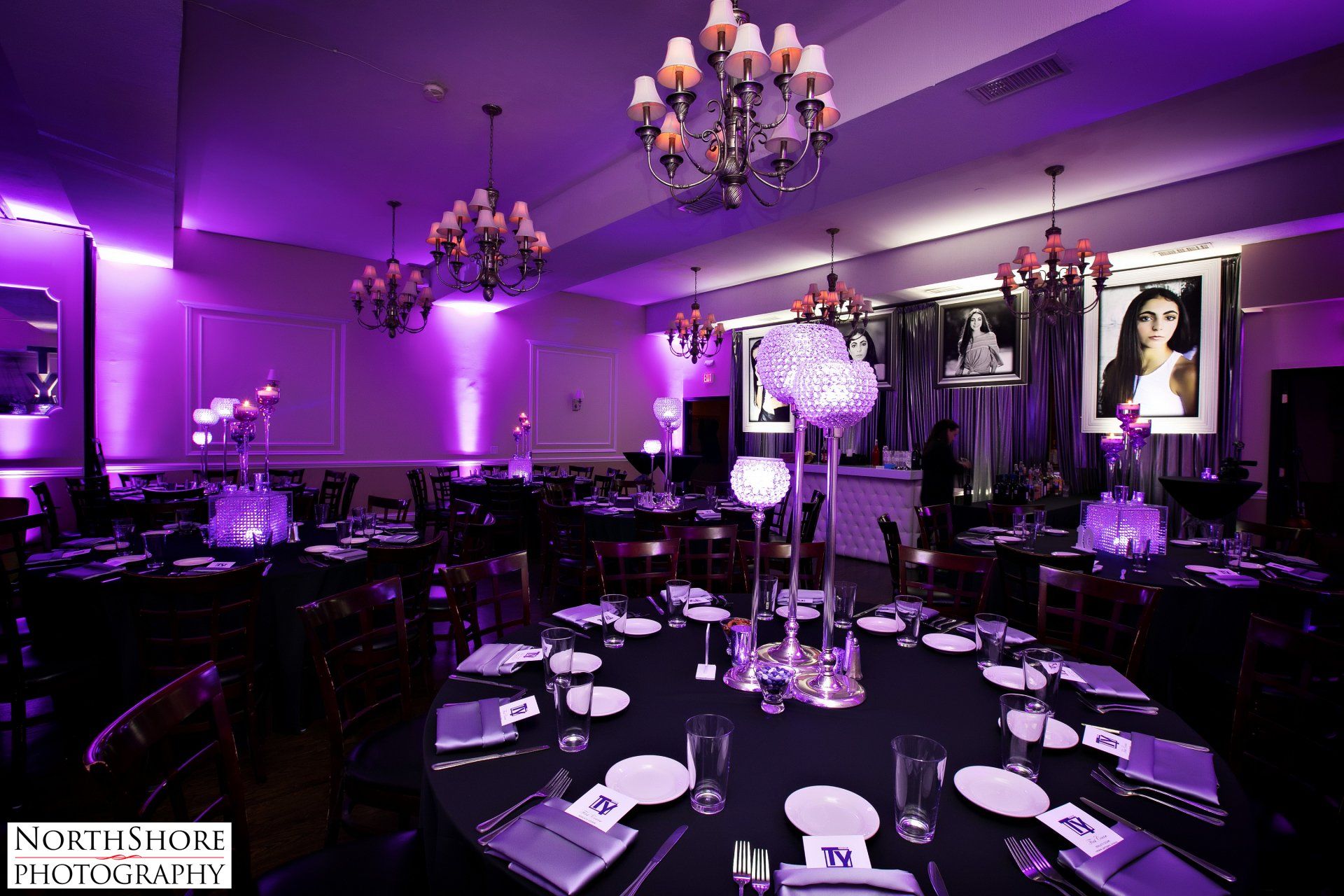 A large room with purple lights and tables set for a party