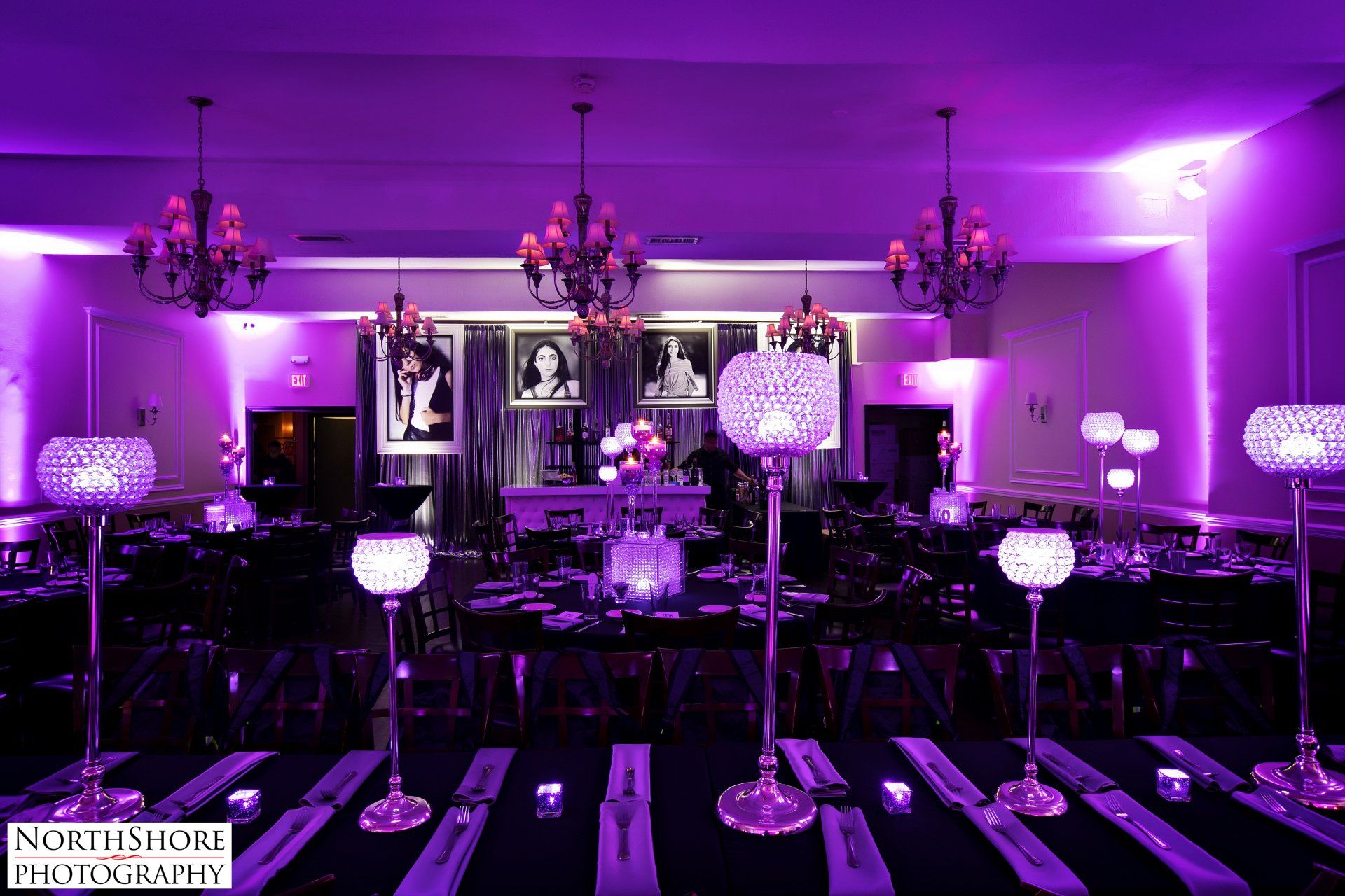 A large room with purple lights on the walls and tables.