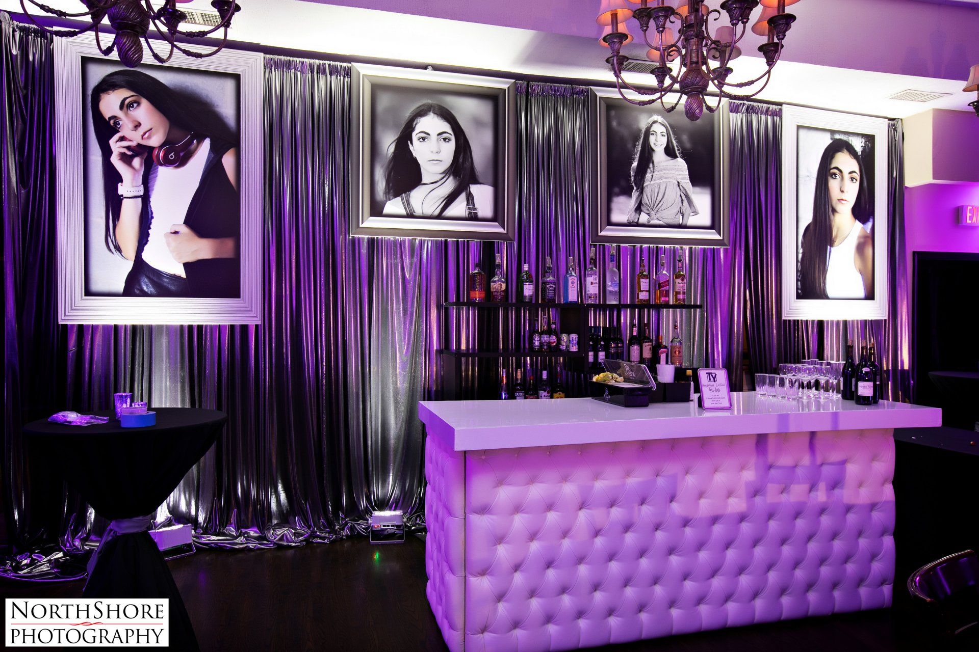 A bar in a room with purple curtains and pictures of women on the wall.