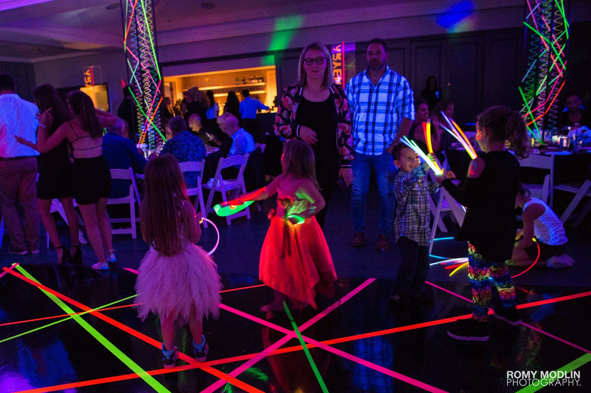 A group of people are dancing in a room with neon lights.