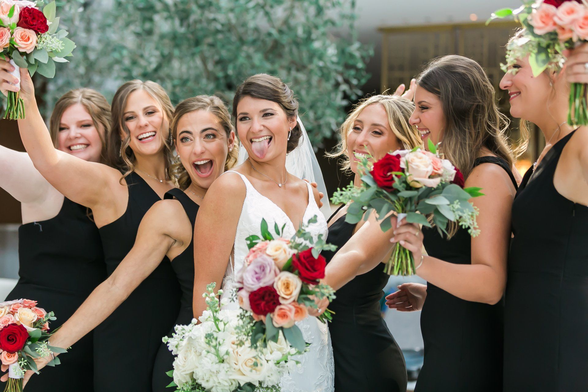 A bride and her bridesmaids are posing for a picture while holding bouquets of flowers.