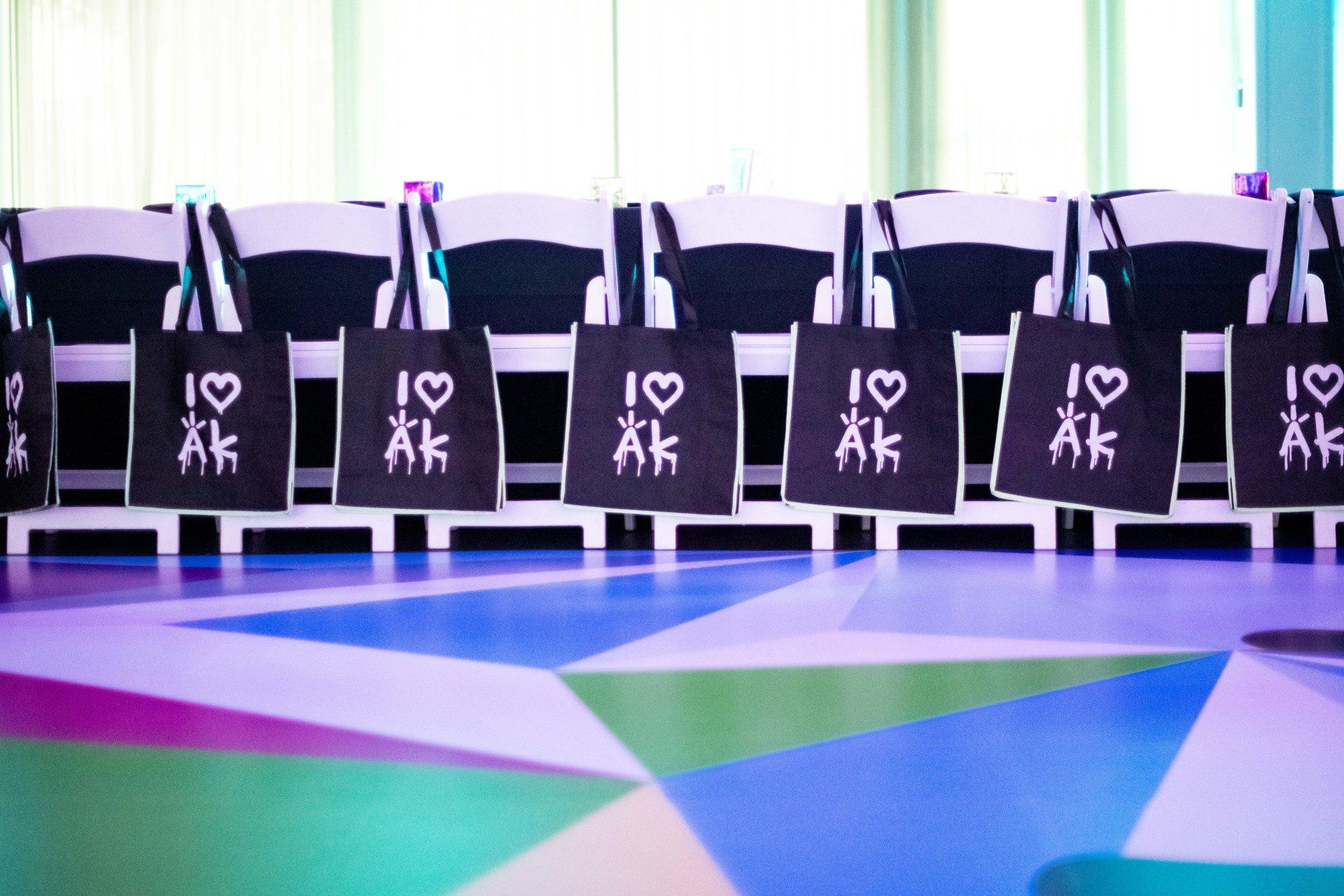 A row of folding chairs with bags on them that say i love ak