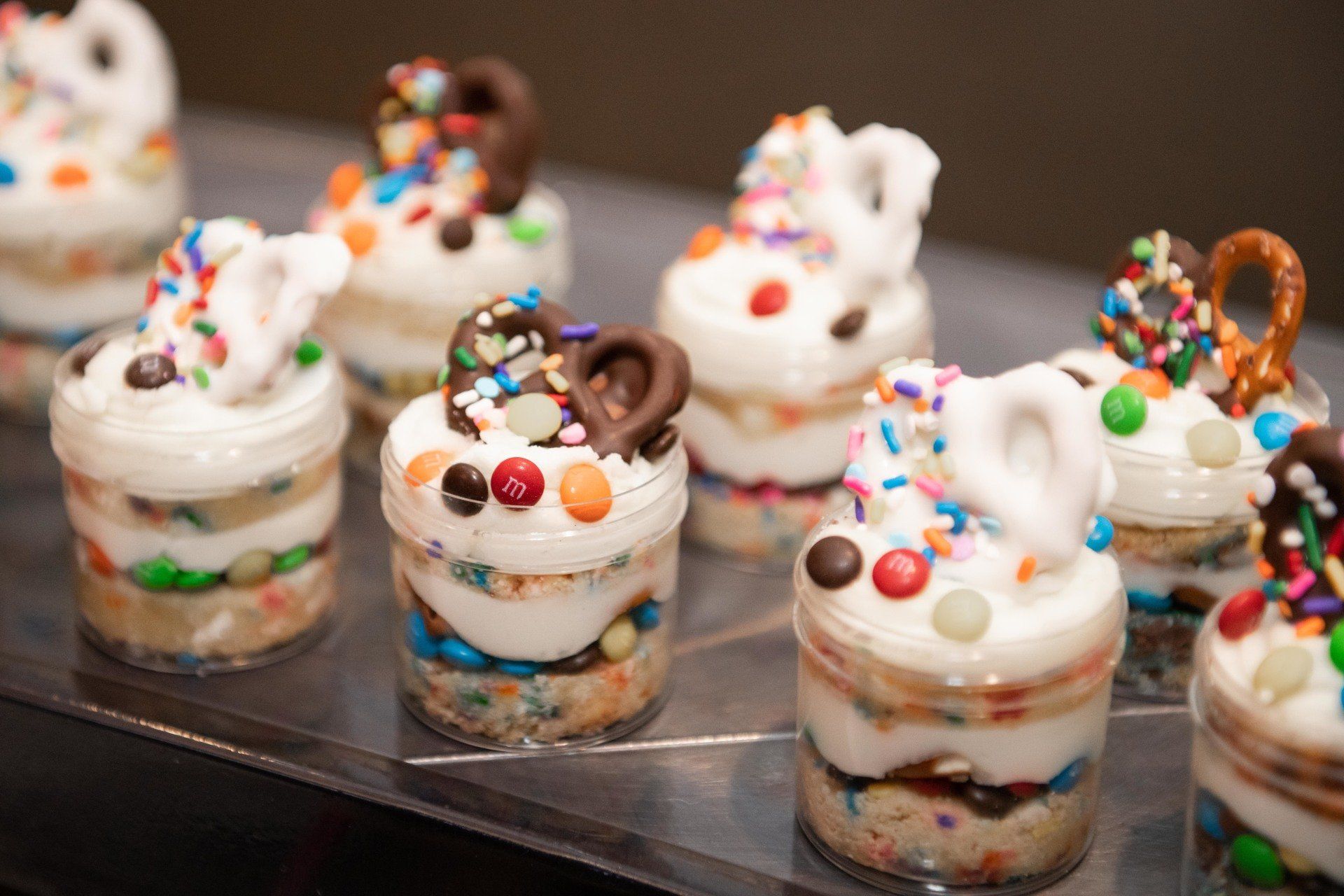 A tray of desserts with sprinkles and pretzels on top.