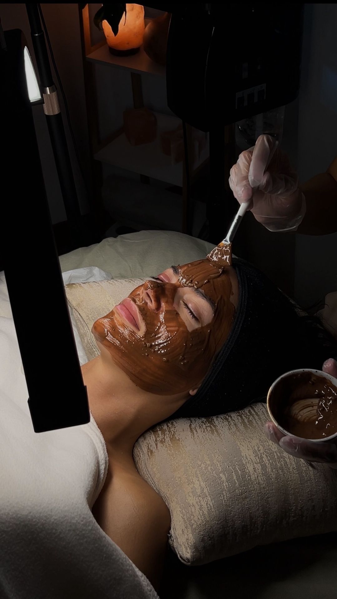 Una mujer se está poniendo una mascarilla de chocolate en la cara.