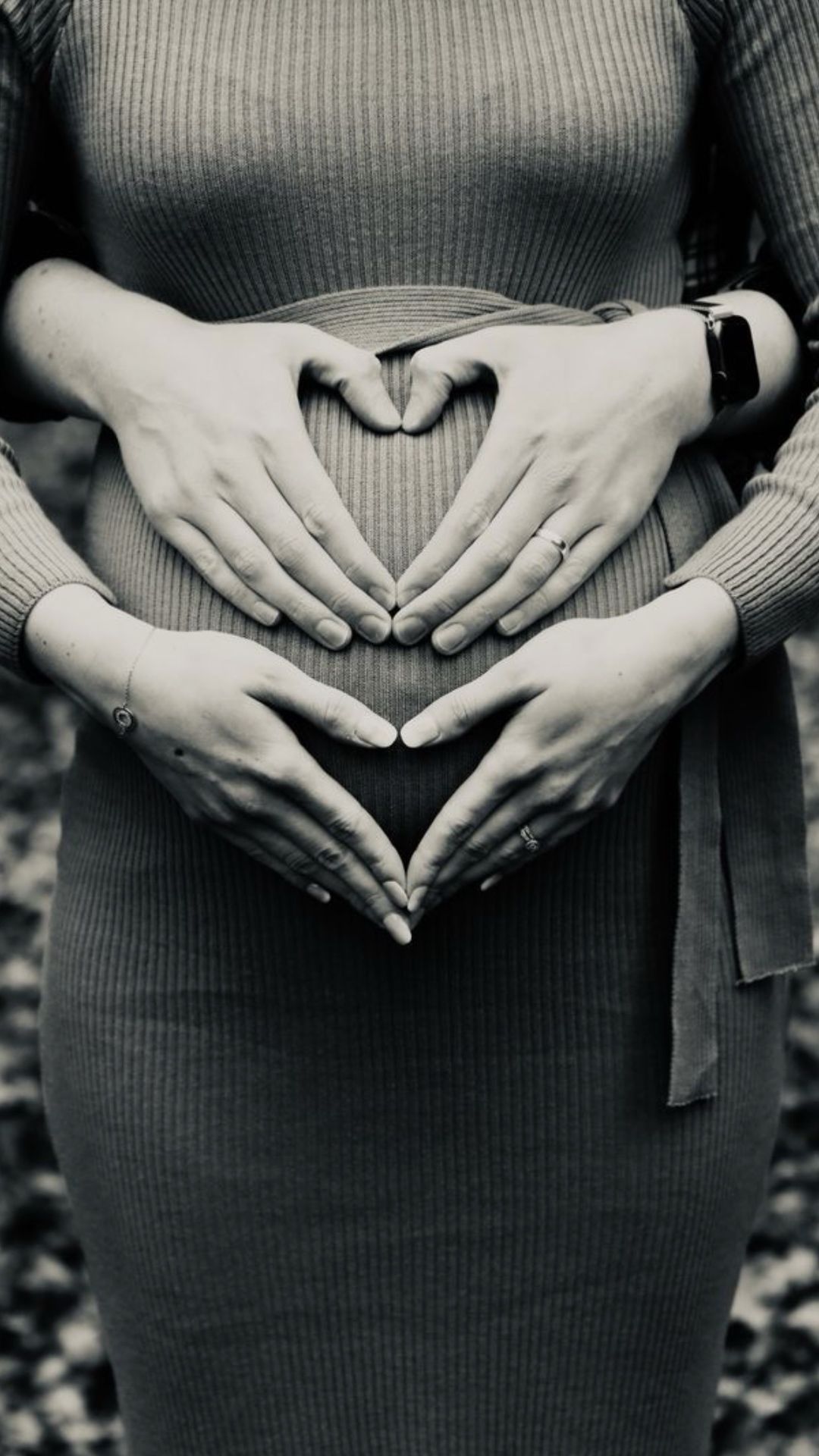 Una mujer embarazada está haciendo forma de corazón con sus manos sobre su vientre.