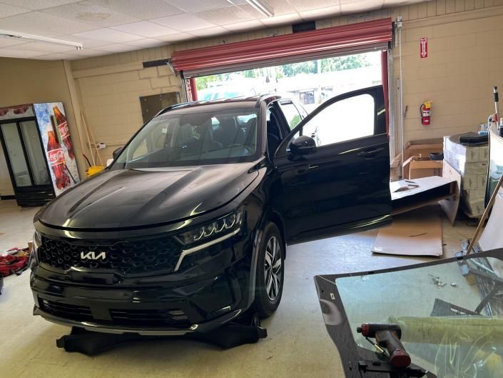 A black Kia SUV parked inside a garage with its driver-side door open.