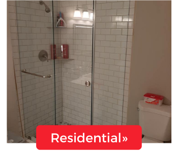 A walk-in shower with white subway tiles and a glass door next to a toilet, featuring a red 