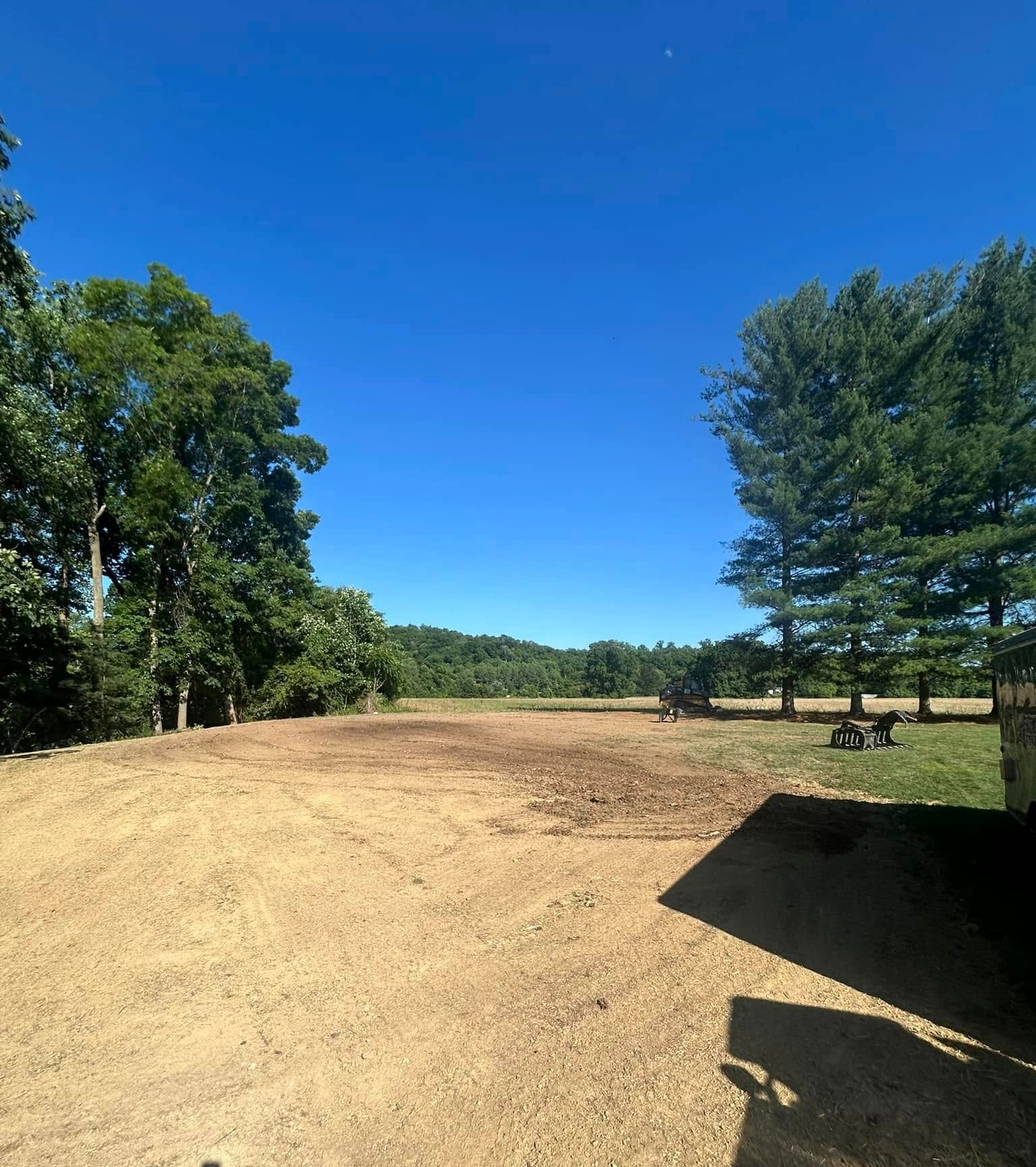 A dirt road with trees in the background and a blue sky