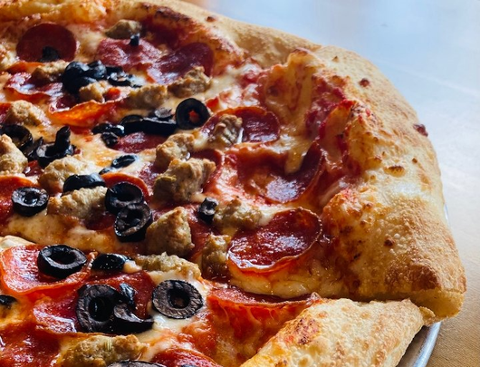Picture of pizza with pepperoni, sausage and olives.