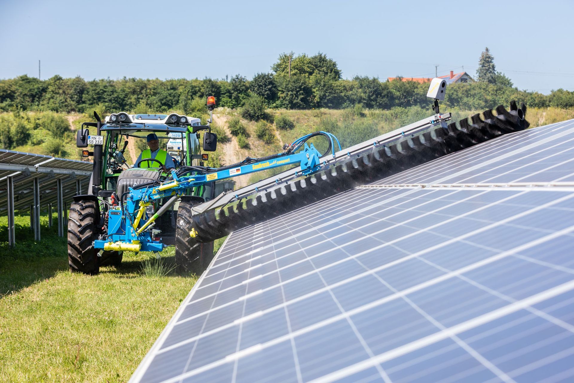 a tractor is cleaning solar panels with a machine .
