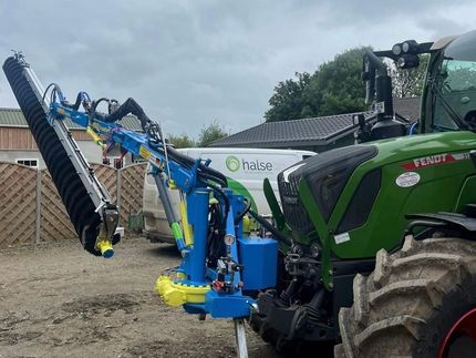 a blue and yellow excavator is cleaning solar panels in a field .