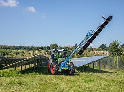 a blue tractor is cleaning solar panels in the snow