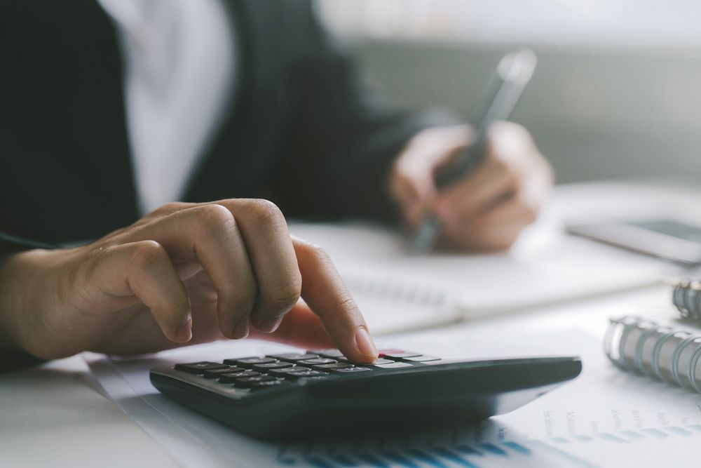 A Person is Using a Calculator and Writing on a Piece of Paper — Commercial Kitchens Direct in Shoalhaven, NSW