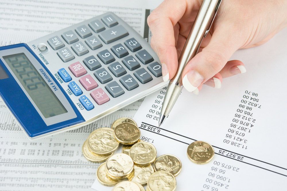 A Person is Writing on a Piece of Paper Next to a Calculator — Commercial Kitchens Direct in Southern Highlands, NSW