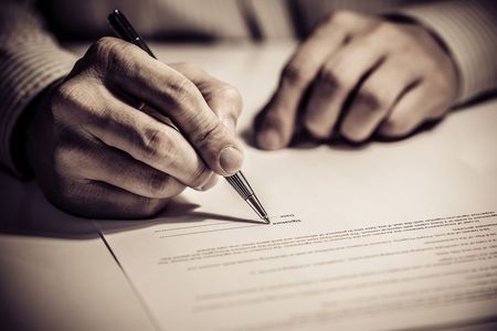 A Person is Writing on a Piece of Paper With a Pen — Commercial Kitchens Direct in Unanderra, NSW