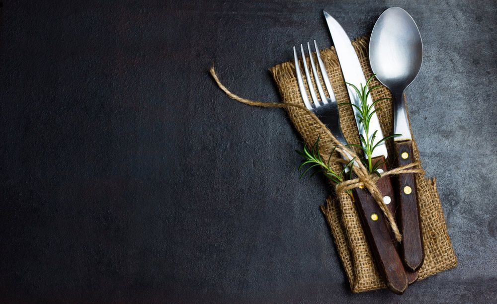 Cutlery Wrapped In Cloth On Black Background — Commercial Kitchens Direct in Southern Highlands, NSW