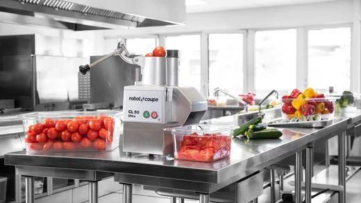 A Kitchen With a Stainless Steel Counter Top Filled With Vegetables and a Machine — Commercial Kitchens Direct in Shellharbour, NSW