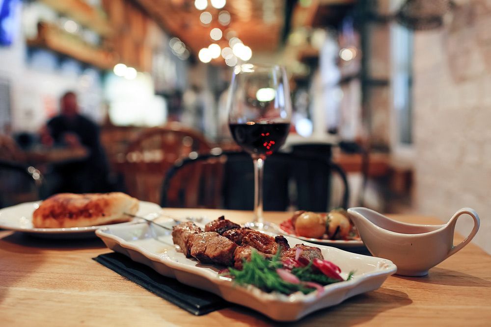 A Plate of Food and a Glass of Wine on a Table in a Restaurant — Commercial Kitchens Direct in Unanderra, NSW