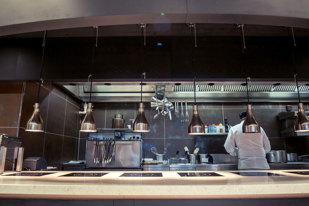 A Chef is Standing Behind a Counter in a Kitchen — Commercial Kitchens Direct in Unanderra, NSW