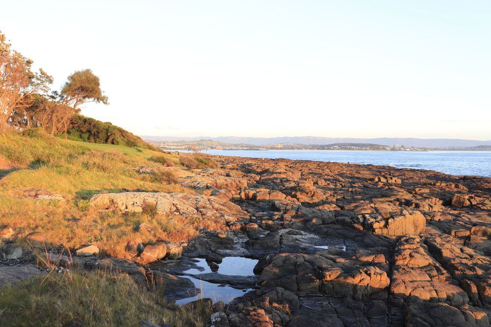 A Rocky Shoreline With a Body of Water in the Background — Commercial Kitchens Direct in Shellharbour, NSW