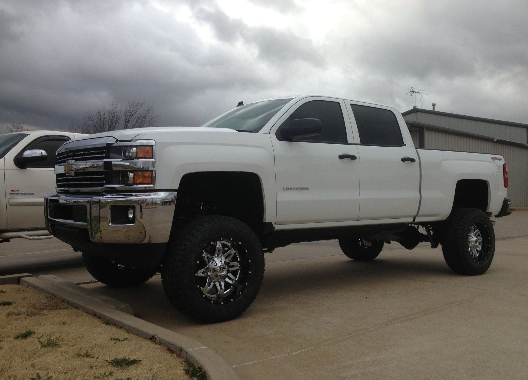 A white truck is parked in a parking lot on a cloudy day.