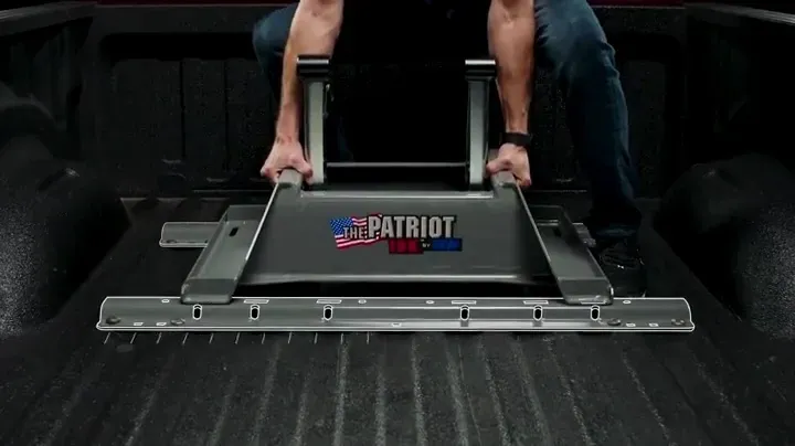 A man is sitting in the back of a truck holding a patriot lift.