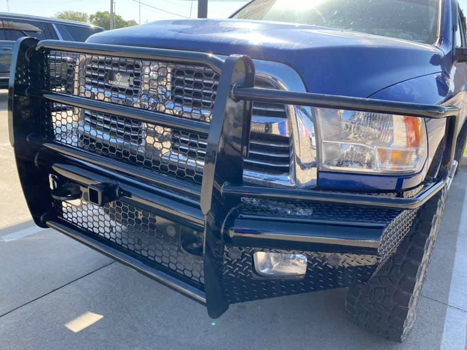 A blue truck with a black bumper is parked in a parking lot.