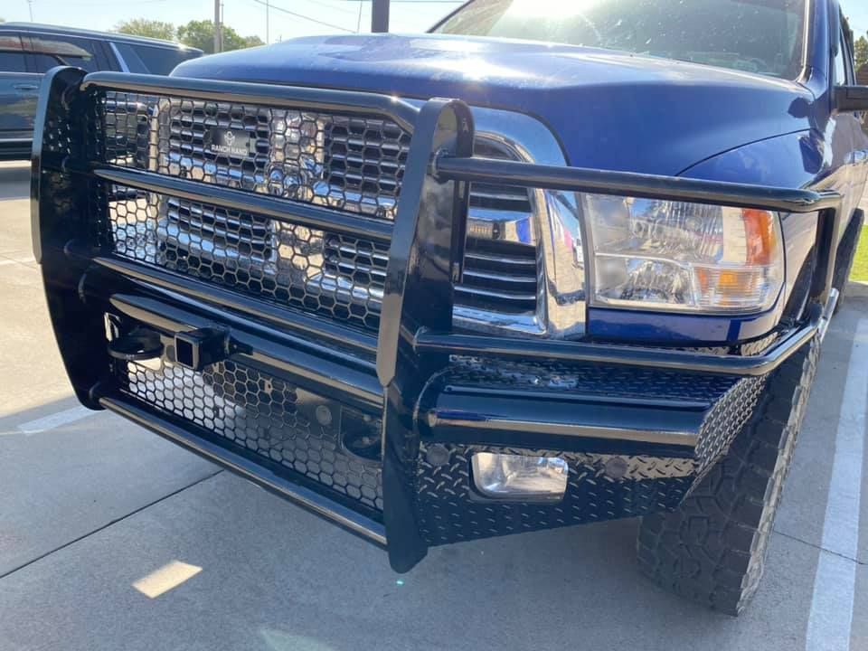 A blue truck with a black bumper is parked in a parking lot.