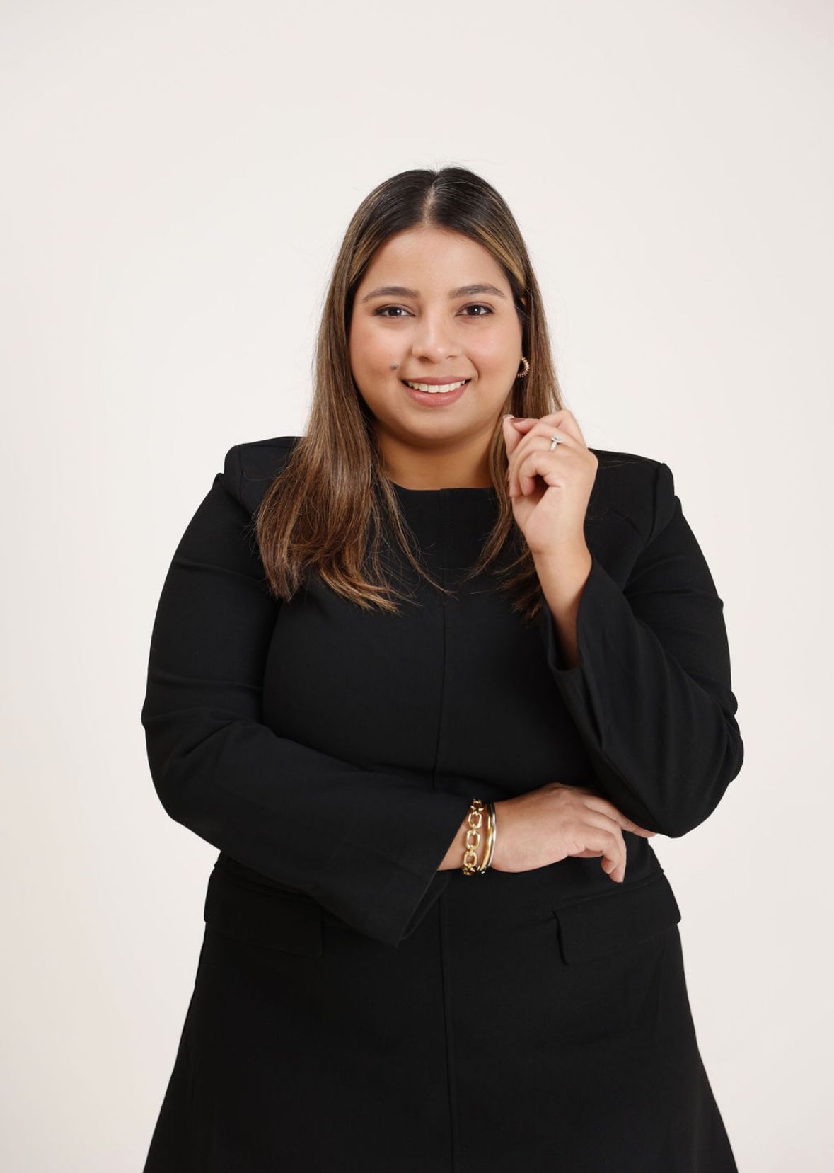 A woman is sitting at a desk with a laptop and a vase of flowers.
