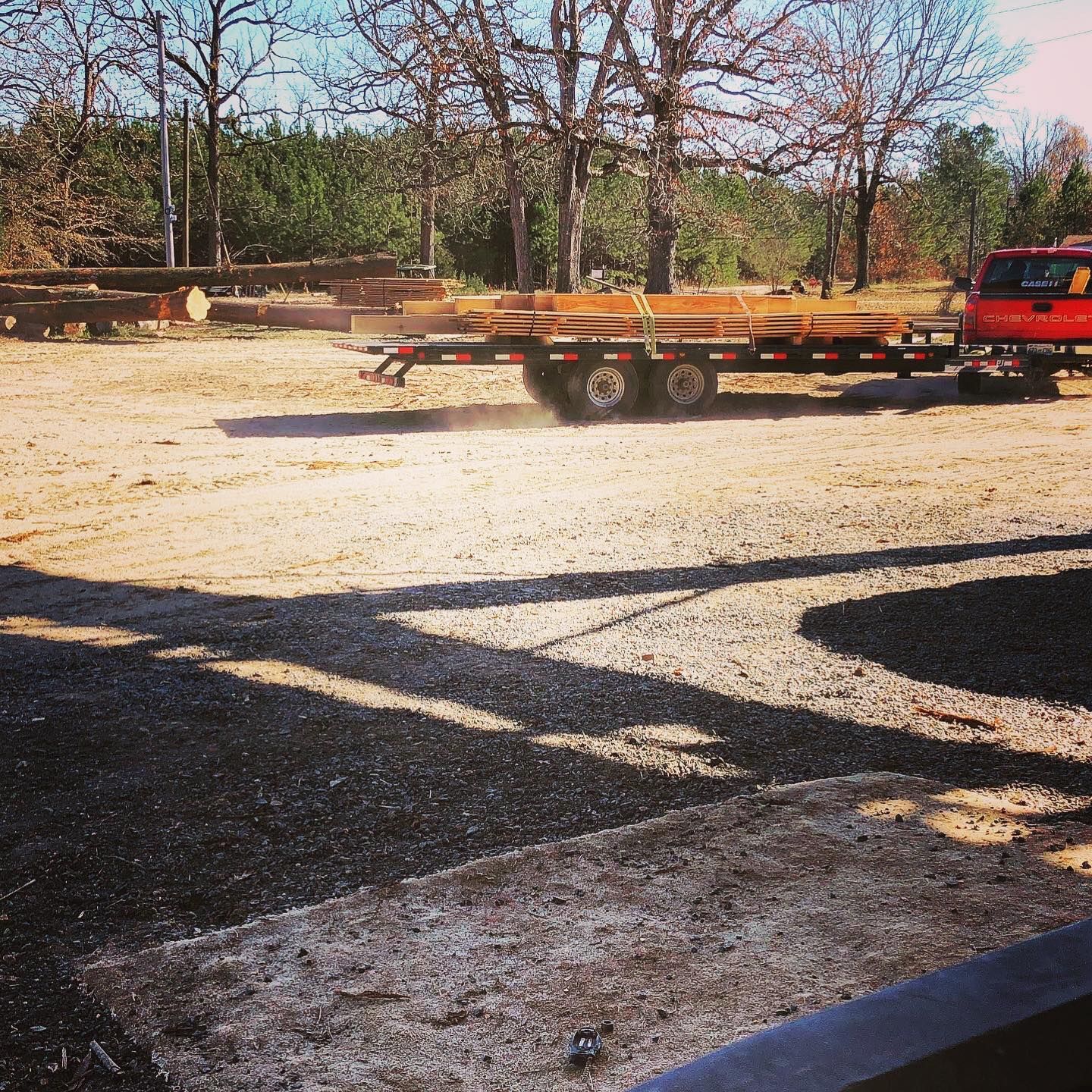 A red truck is pulling a trailer full of logs