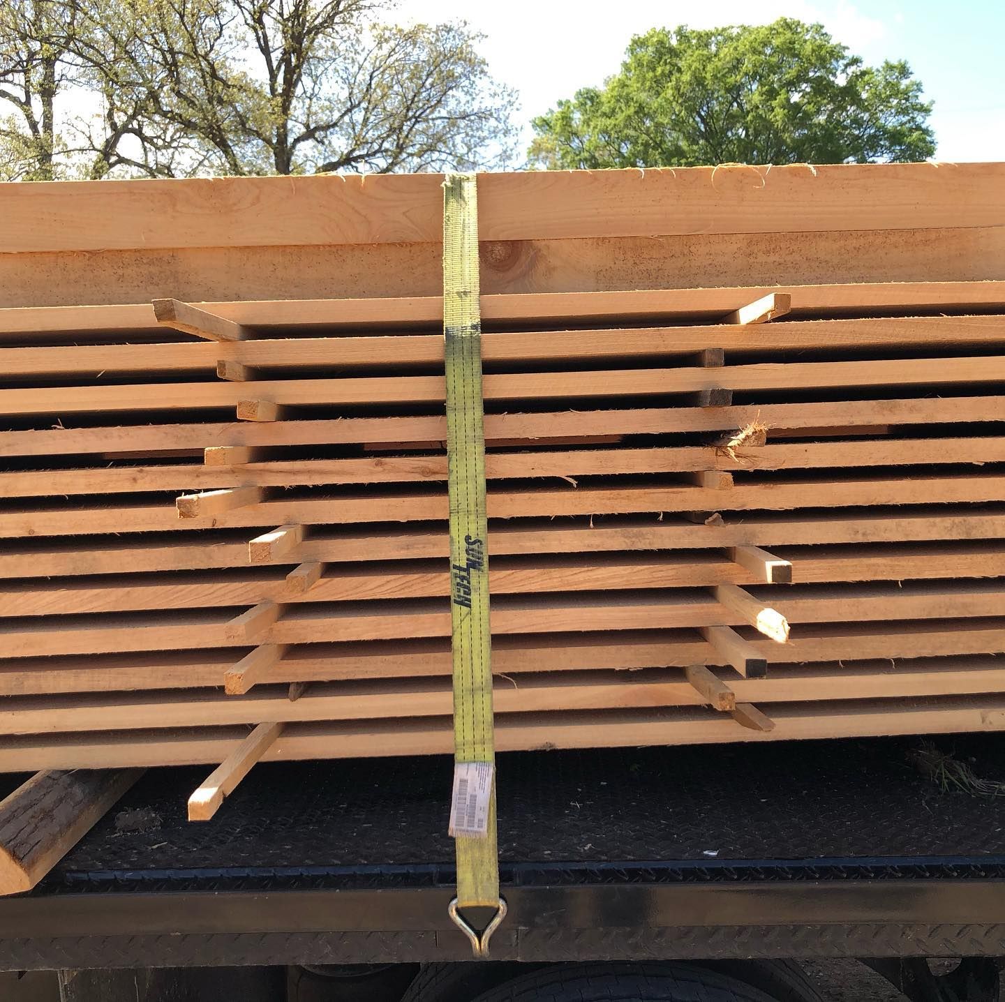 A stack of wood is tied together with a green strap