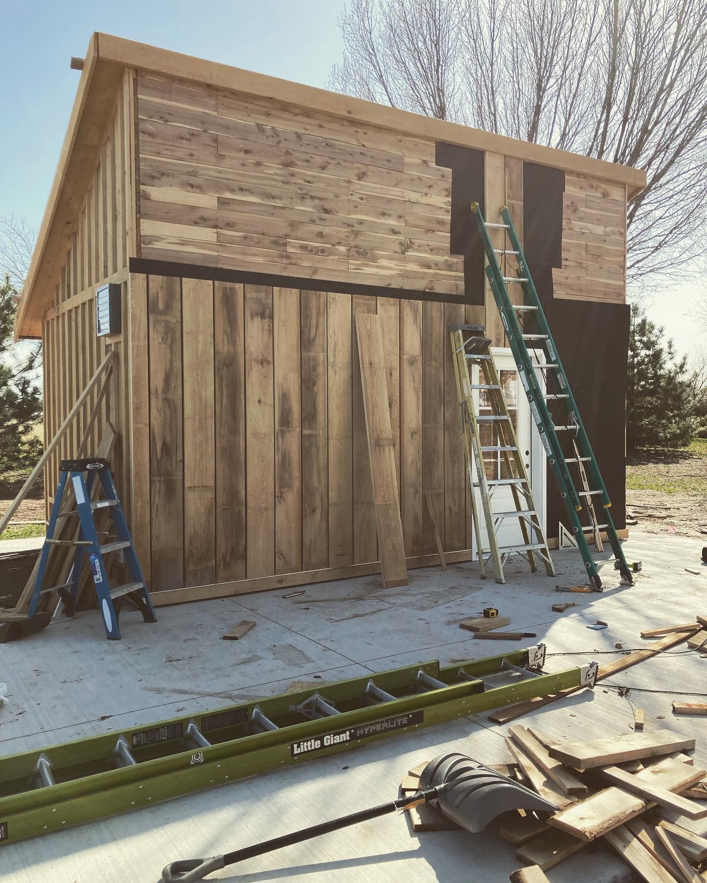A wooden shed is being built with a ladder on the side of it.