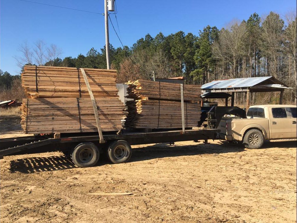 A truck is carrying a trailer full of wood.