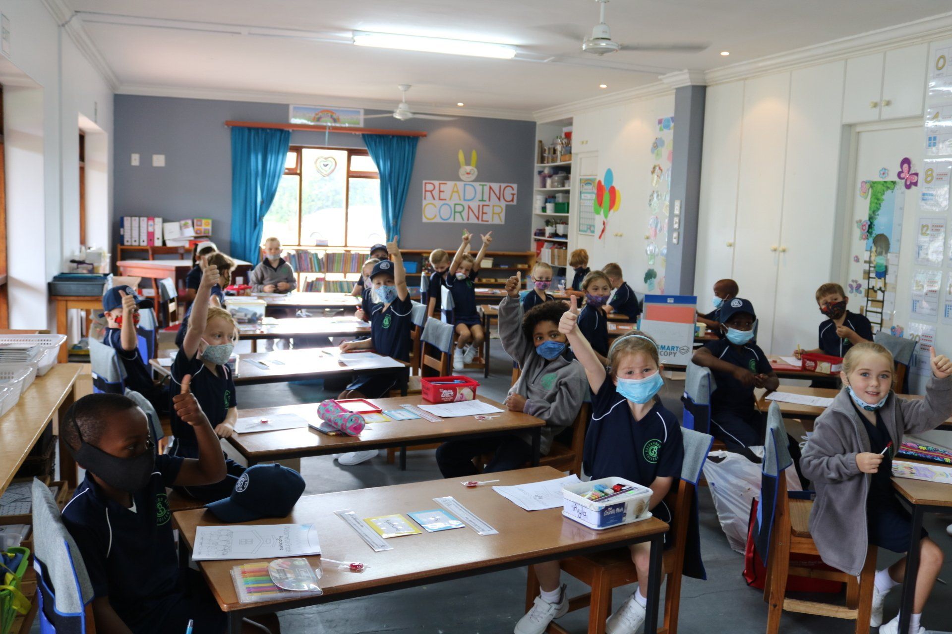 a group of children are raising their hands in a classroom .