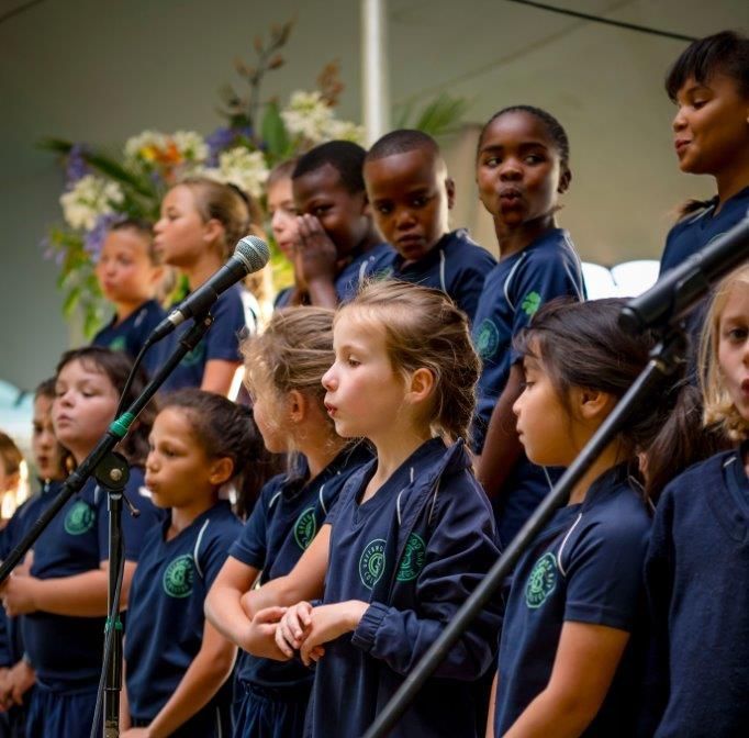 a group of children are raising their hands in a classroom .