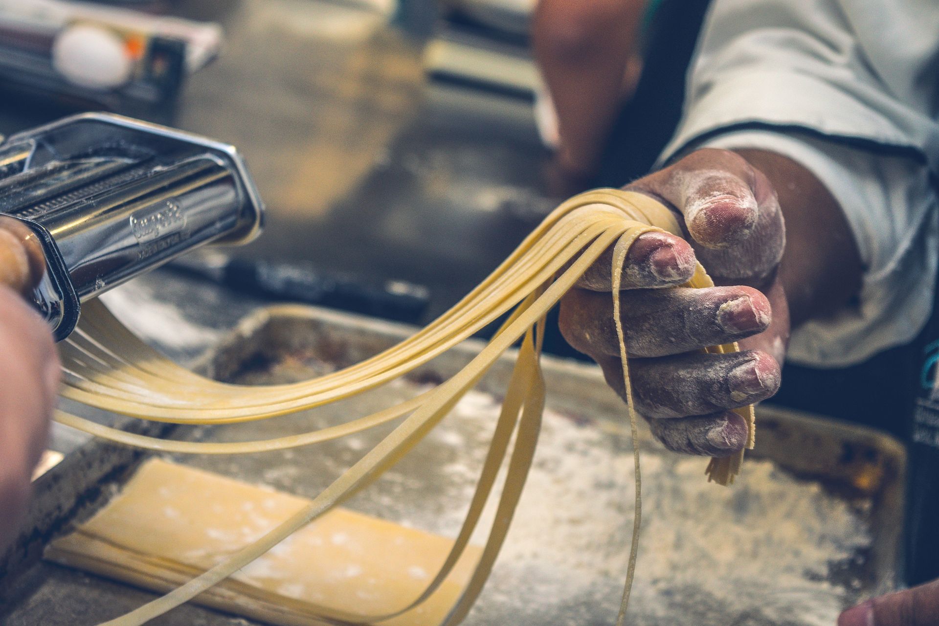 A person is making noodles with a pasta machine.