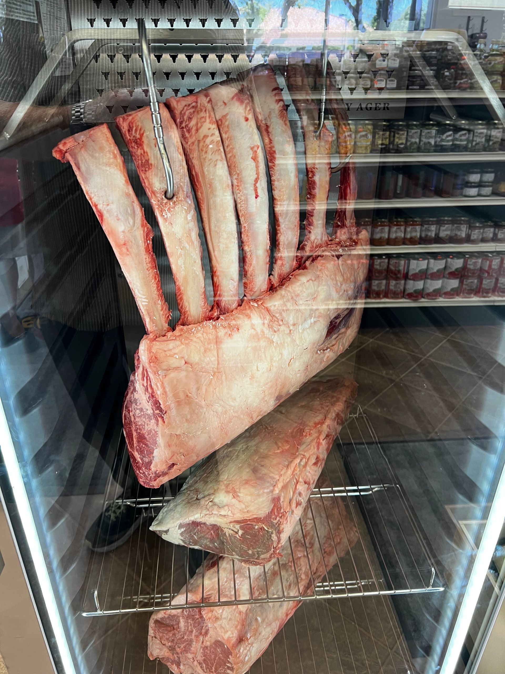 A bunch of meat is hanging in a refrigerator.
