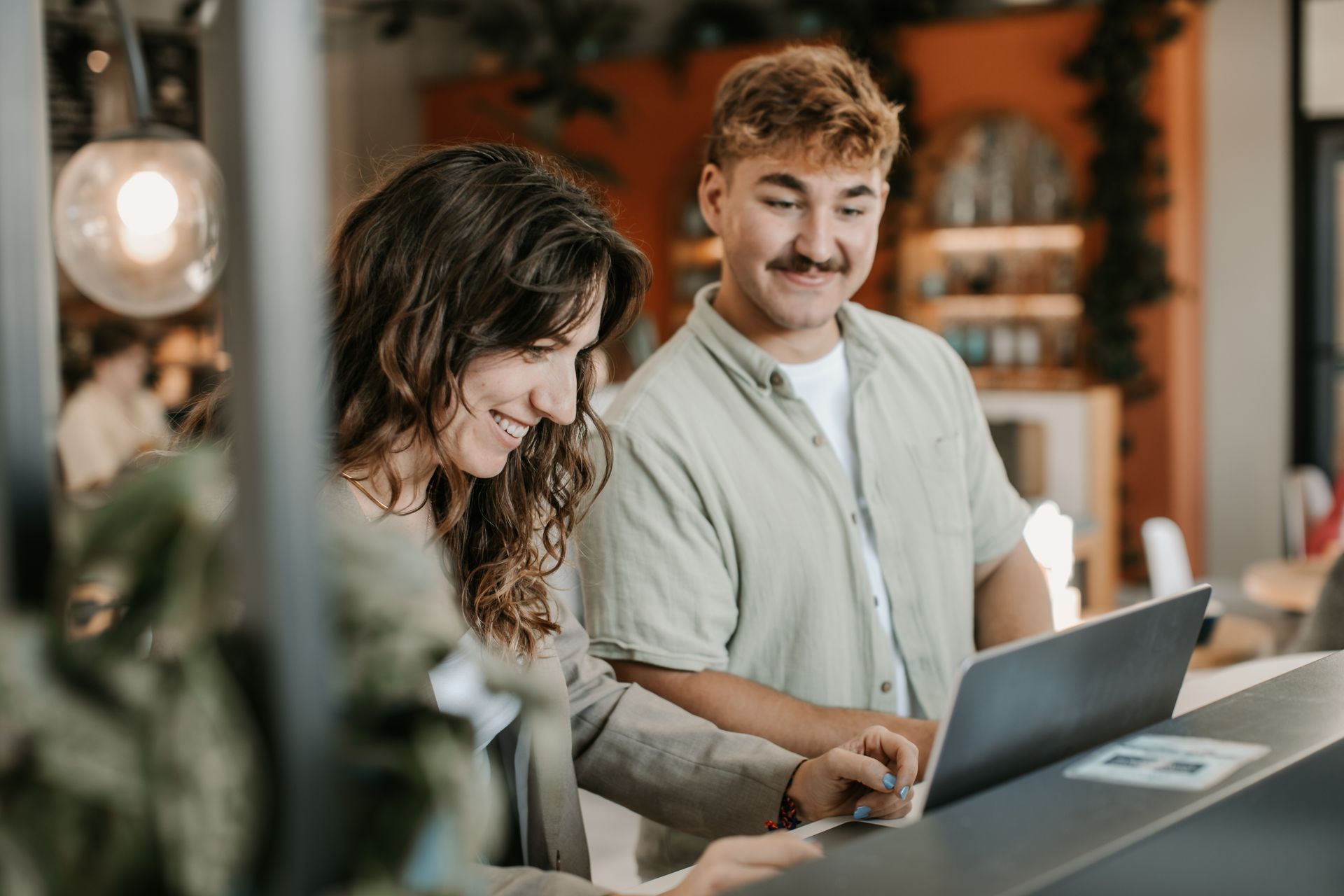 Two coworkers collaborate in front of a laptop. 