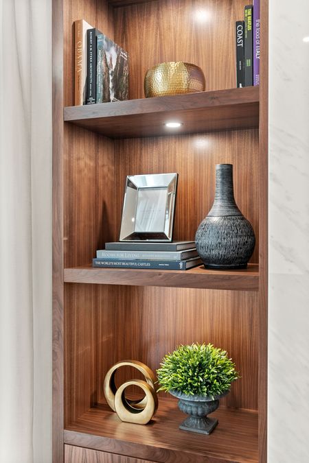 Wooden bookshelf with decorative items: books, vases, and golden accents.