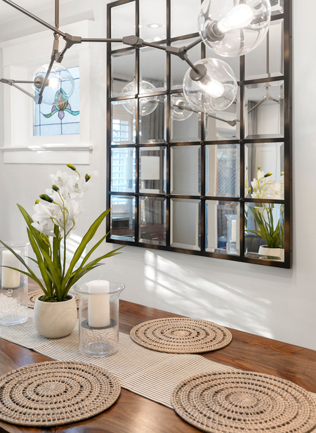 Dining table with centerpiece, mirror, and light fixture; neutral tones.
