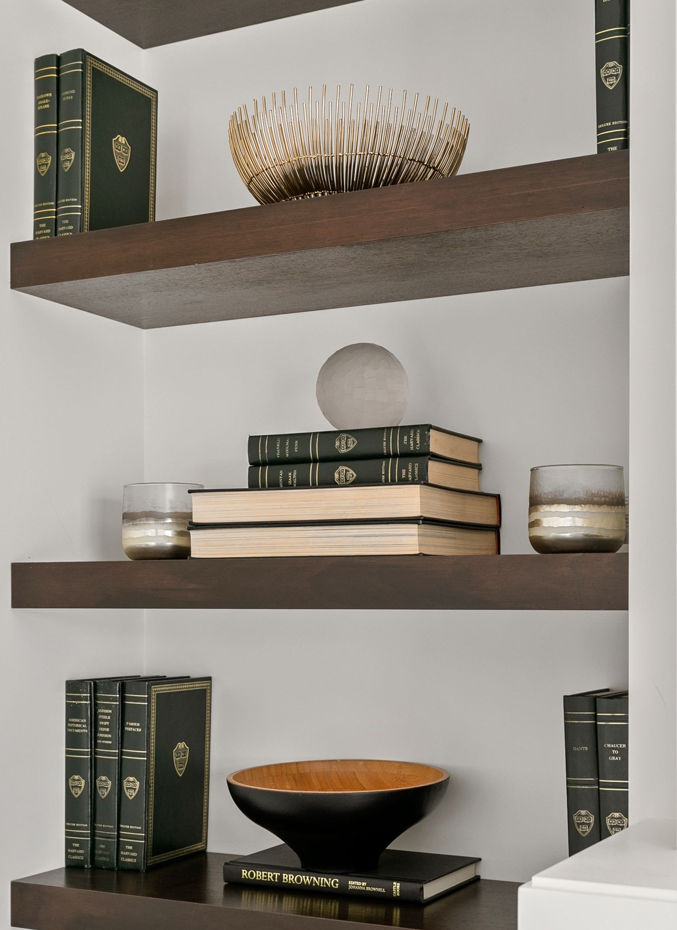 Built-in dark wood shelves displaying books, decorative bowl, and globe, against white walls.