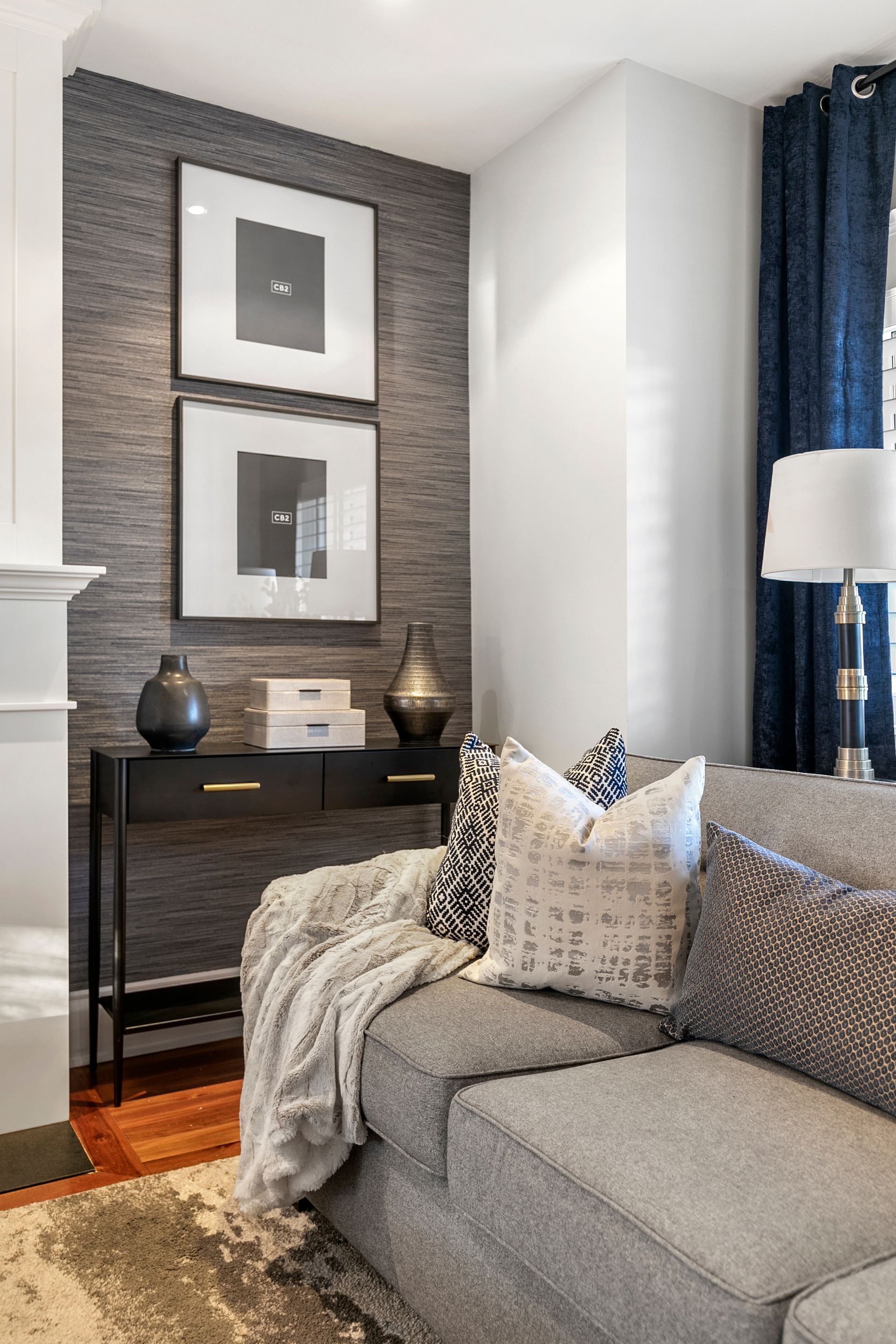 Gray sofa in modern living room; dark console table with decor; framed art on textured gray wall.