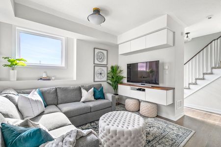 Cozy living room with gray sectional sofa, TV on floating shelf, and white storage cabinets.