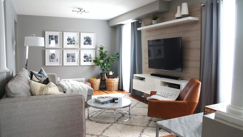 Cozy living room with gray walls, gallery wall, TV on wood paneling, and leather armchair.