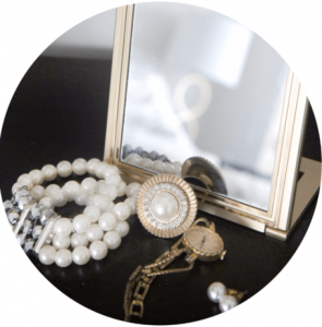Jewelry and a small mirror arranged on a black surface.