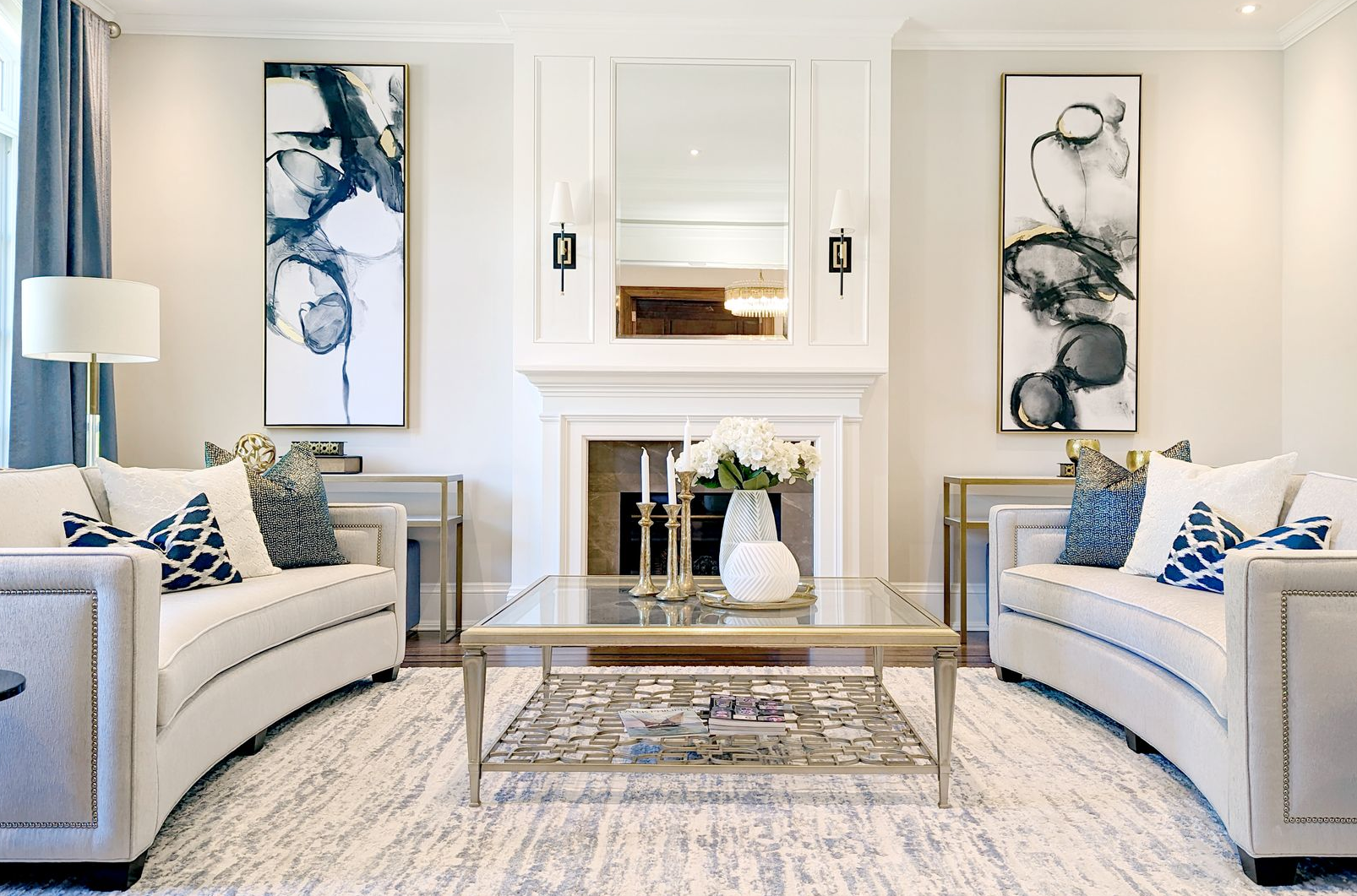 Living room with matching white sofas, artwork, fireplace, and blue accents.